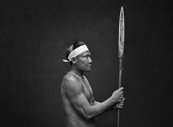 Native Amazonian Indian man holds a spear vertically.