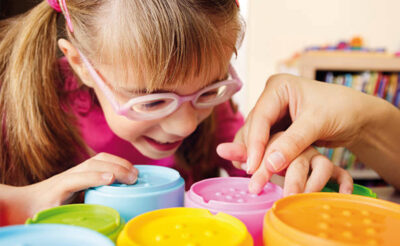 Little girl with eyeglasses touches her toys.