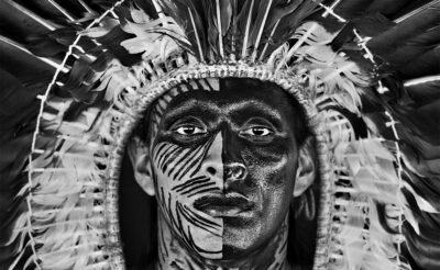 Amazonian Indian man with painted face and a feather headdress.