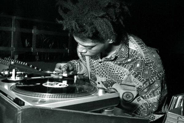 Basquiat manipule l'aguille d'une platine. Il regarde le vinyle tourner.